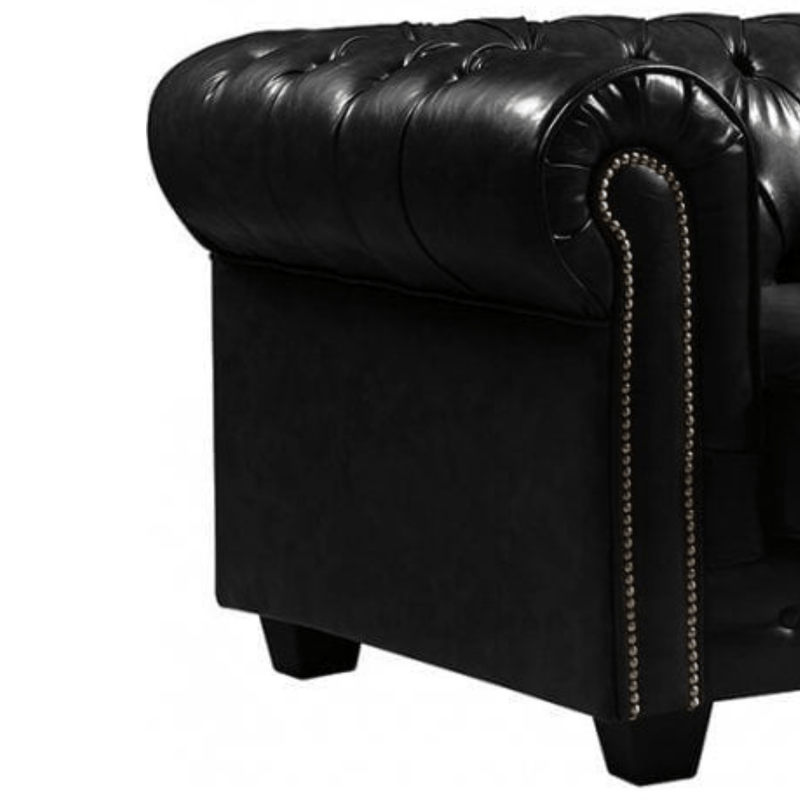 Close-up of a black leather armchair with tufted backrest and nailhead trim on a white background.