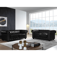 Black leather sofas in a modern living room with large windows.