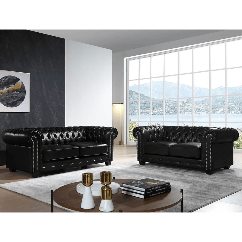 Black leather sofas in a modern living room with large windows.