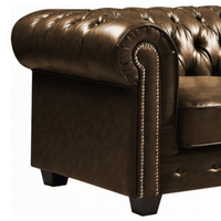 Brown leather sofa with tufted backrest and nailhead trim on a white background