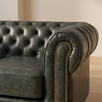 Chesterfield Green Leather Antique 2 seater sofa close-up of the rolled arm and brass nailhead trim in a living room setting