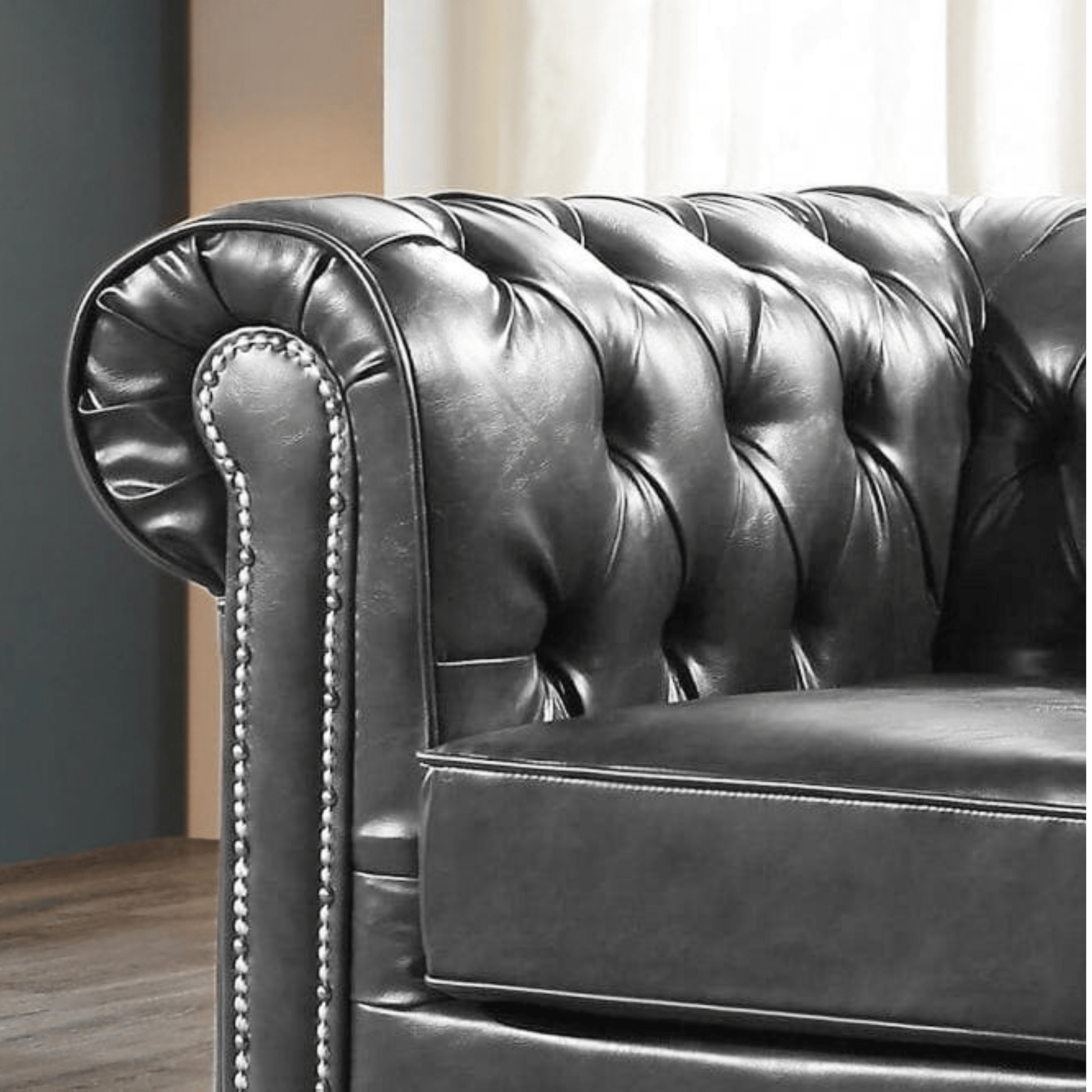 Close-up of a dark leather Chesterfield sofa with tufted backrest.