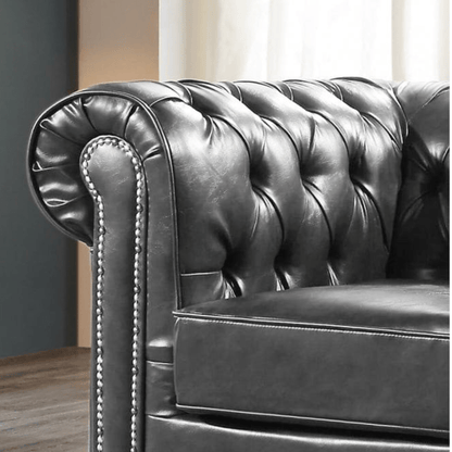 Close-up of a dark leather Chesterfield sofa with tufted backrest.