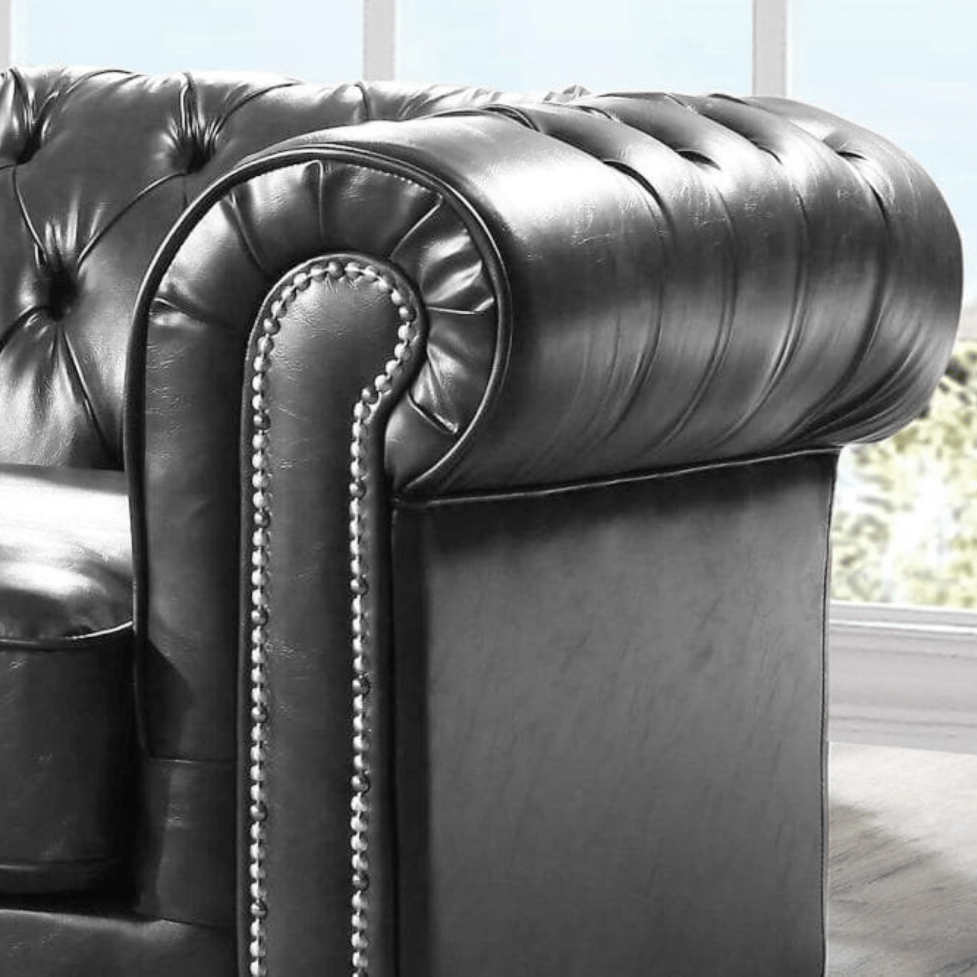 Close-up of a dark gray leather armchair with tufted backrest and armrests.
