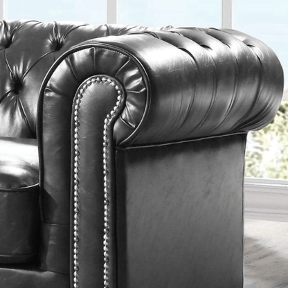 Close-up of a dark gray leather armchair with tufted backrest and armrests.