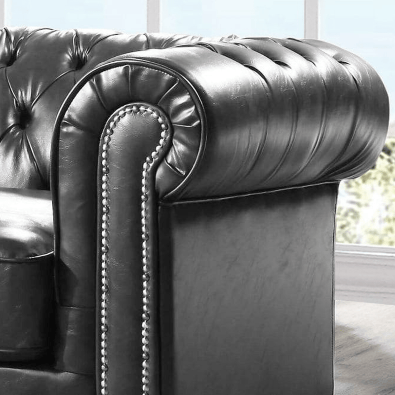 Close-up of a dark gray leather armchair with tufted backrest and armrests.