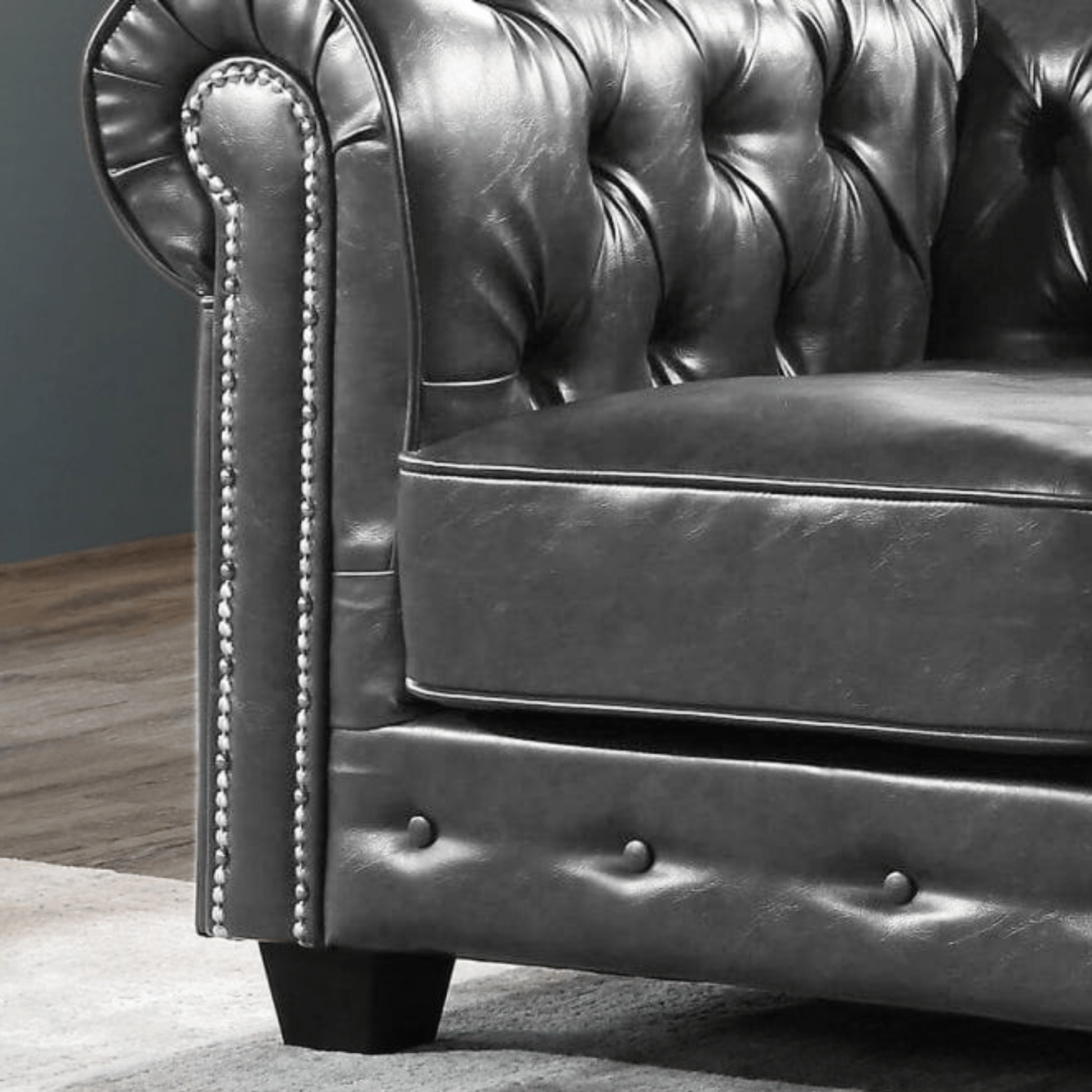 Close-up of a dark leather sofa with buttoned backrest and armrests.