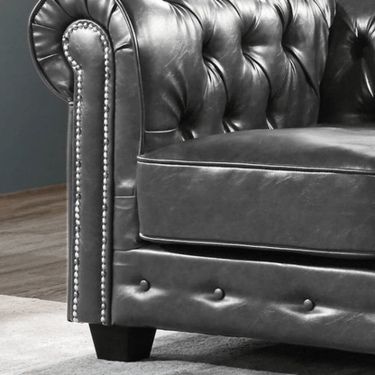 Close-up of a dark leather sofa with buttoned backrest and armrests.