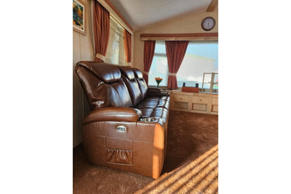 Tan electric leather recliner three-seater sofa with 2 built-in cup holders in a modern living room setting, side view