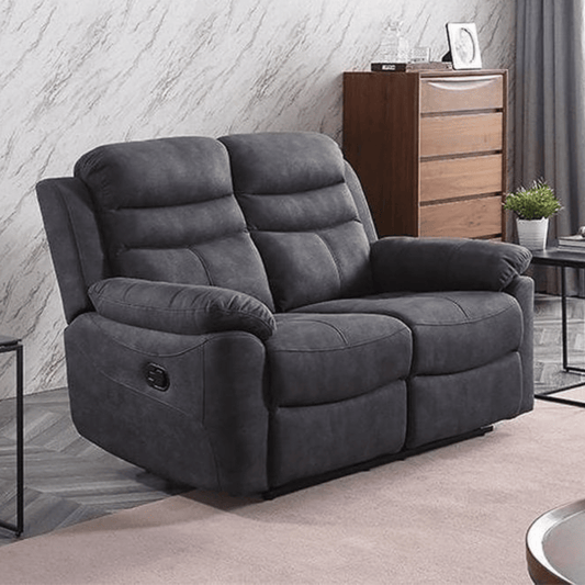 Gray recliner sofa in a living room setting with a wooden cabinet and plant in the background.