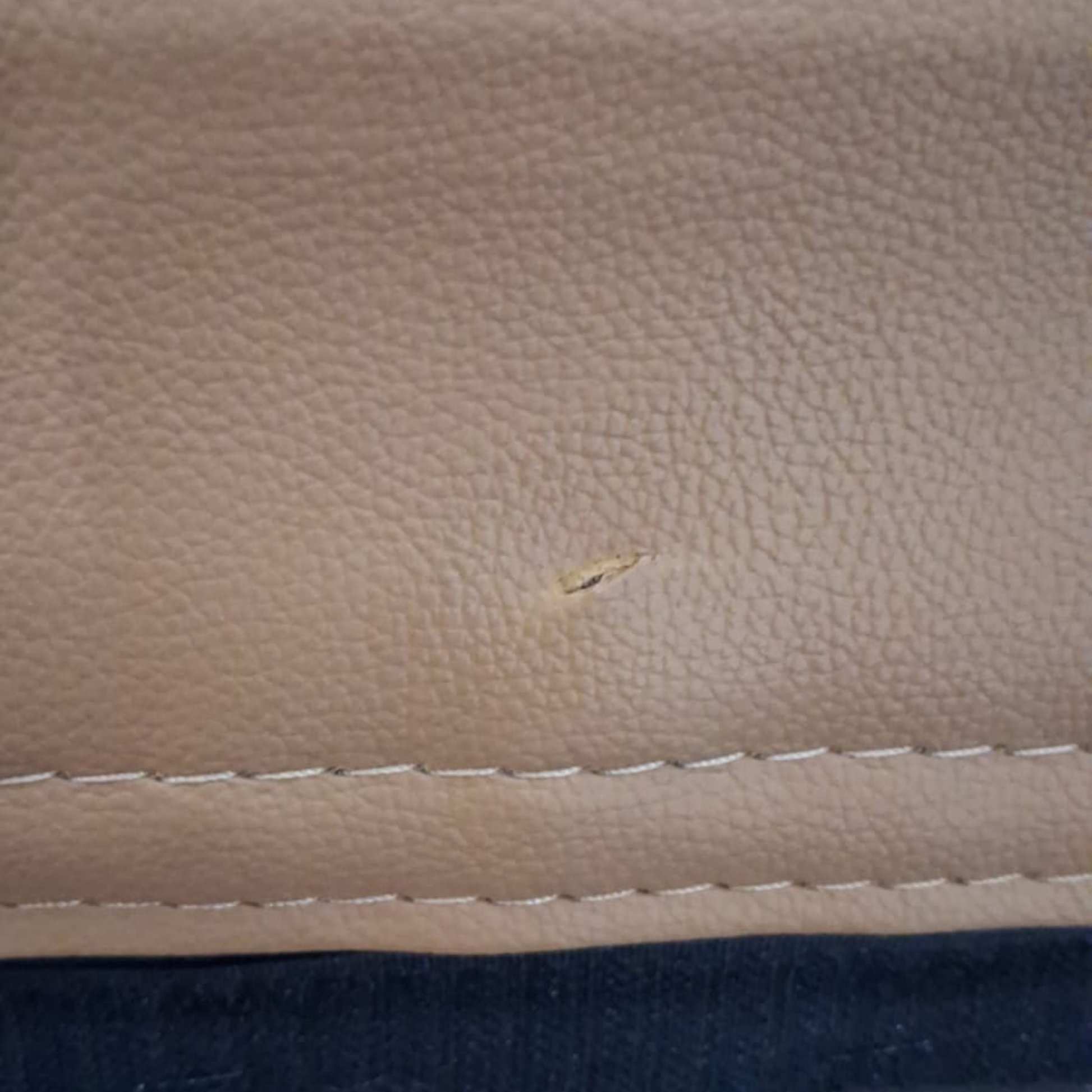 Close-up of a beige leather surface with a small scratch.