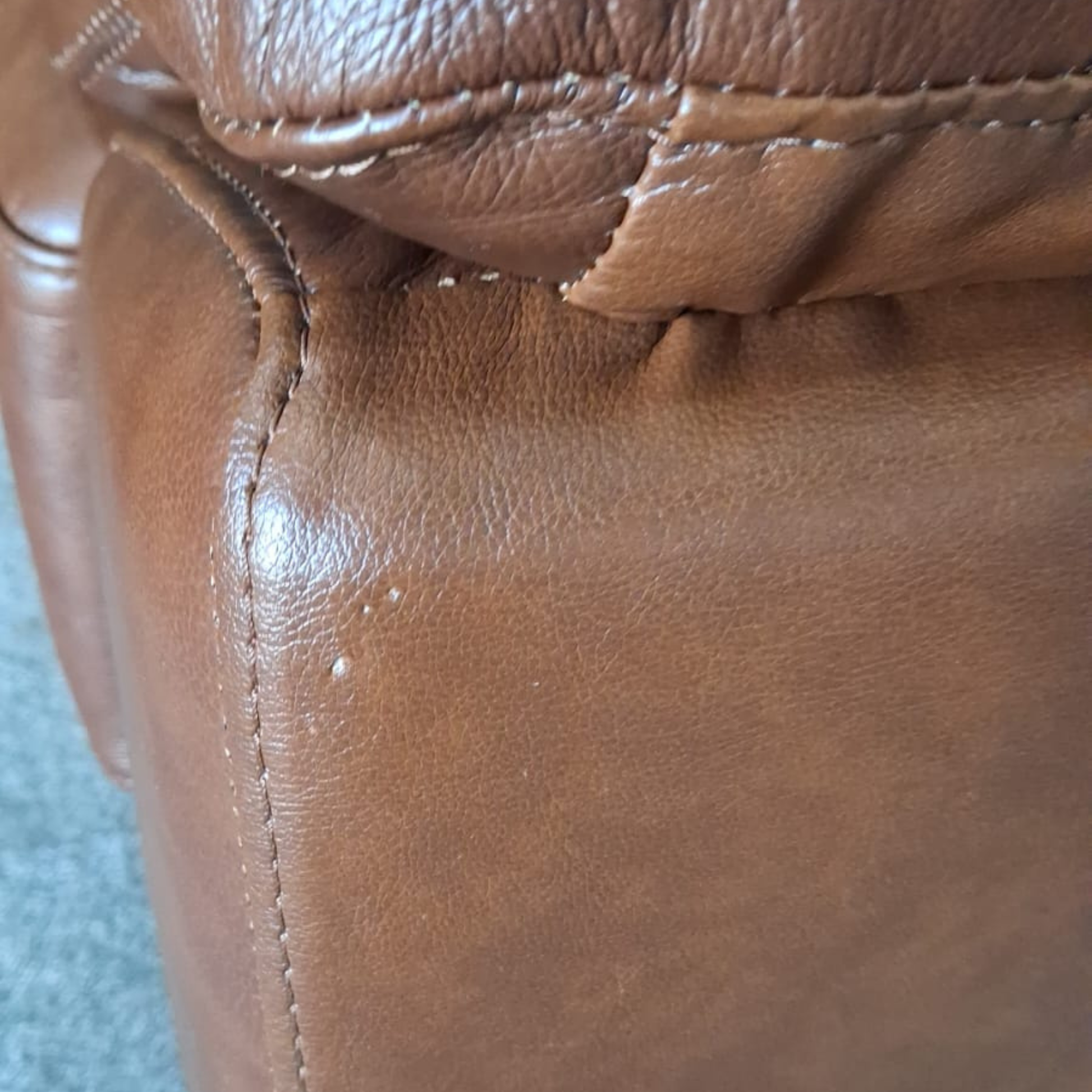 Close-up of a brown leather surface with visible wear and tear.