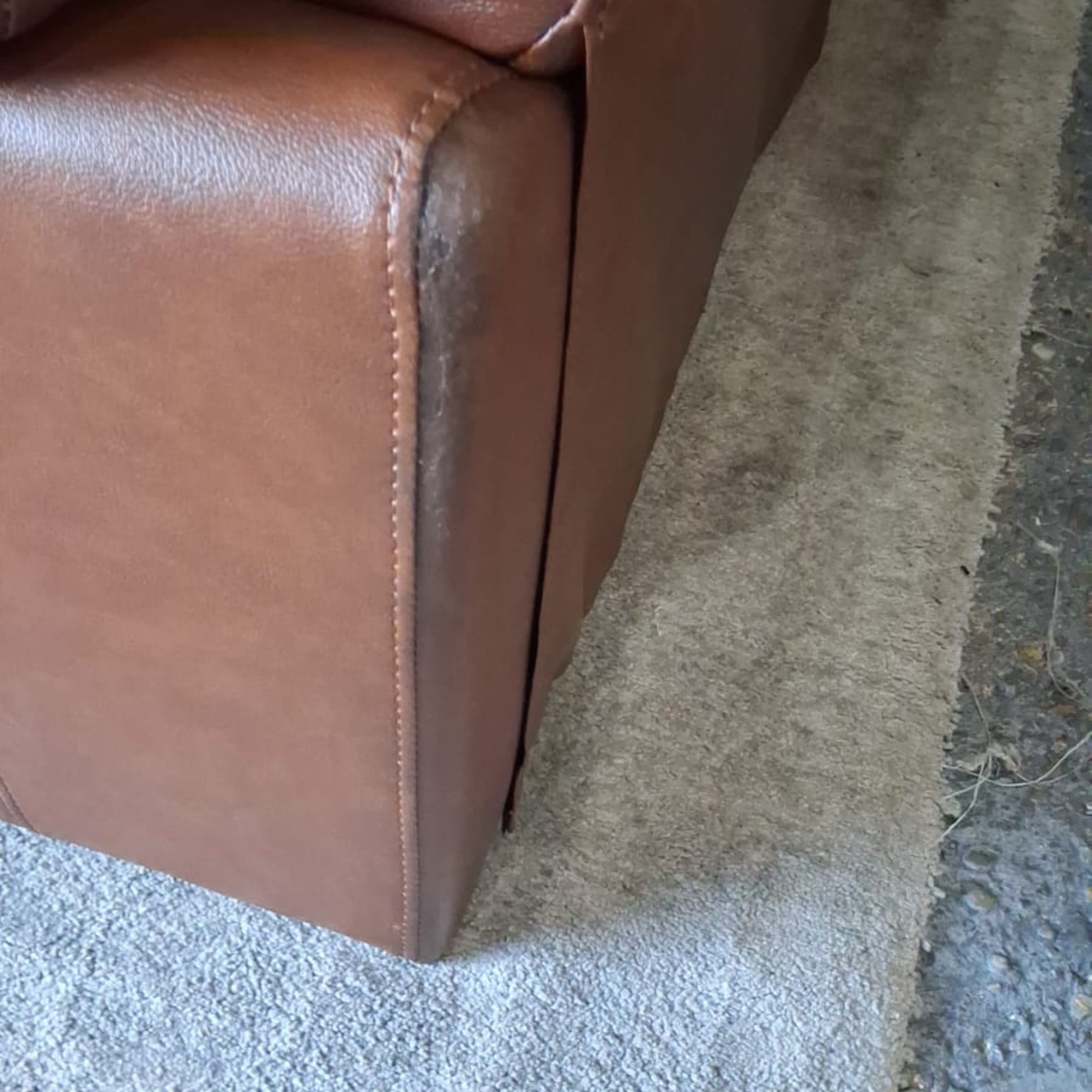 Brown leather armchair corner on a textured surface