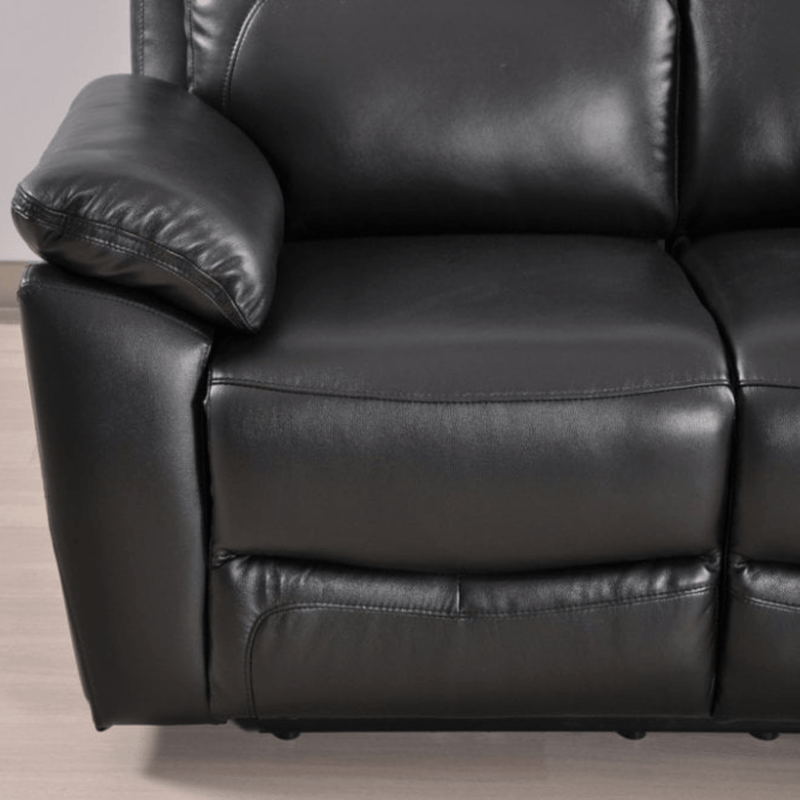 Close-up of a black leather recliner sofa on a light wooden floor.