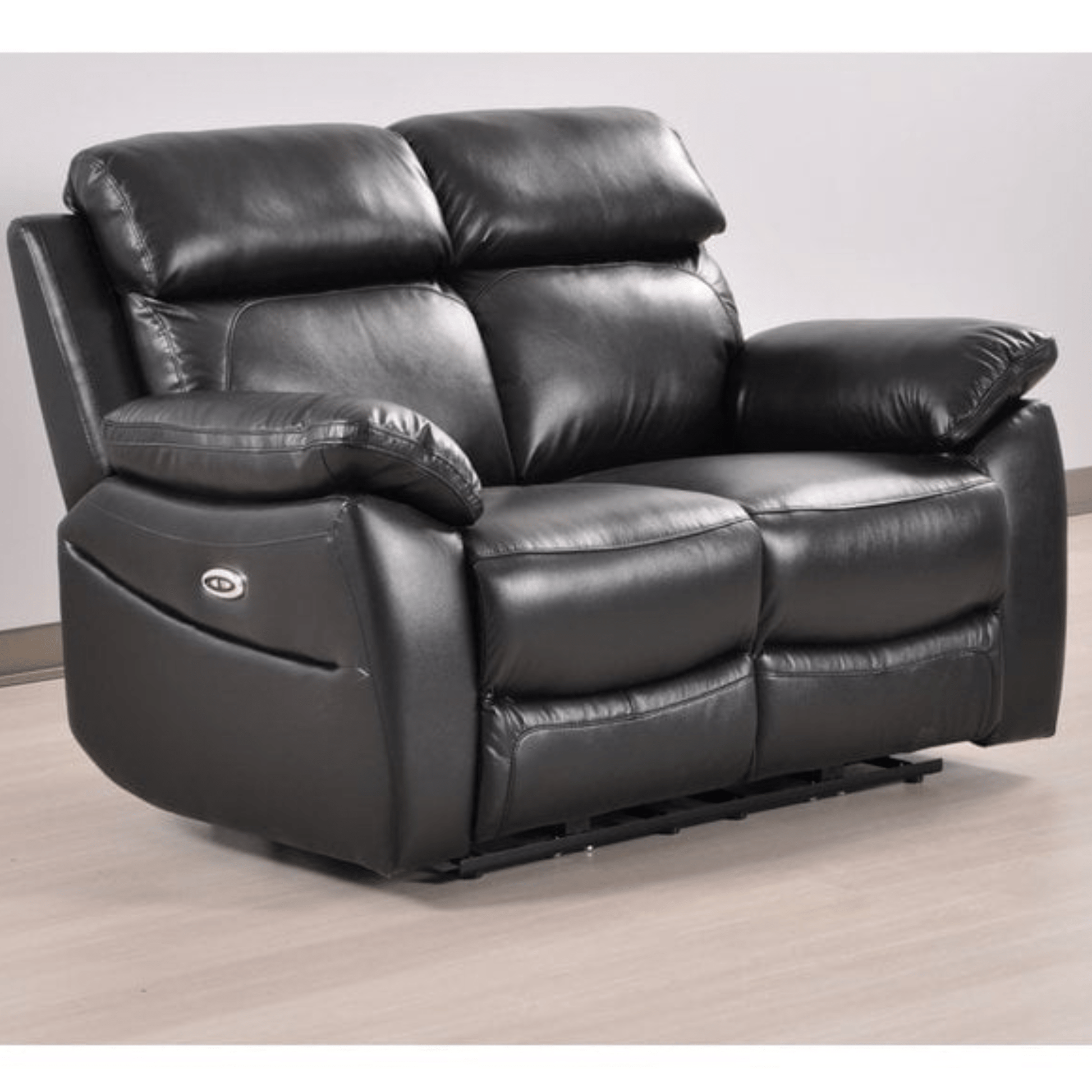 Black leather recliner sofa on a light wooden floor with a white wall background