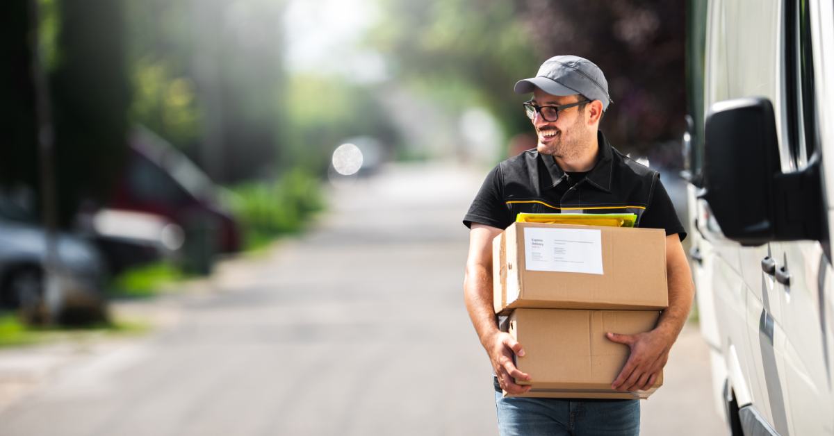 Man holding a package with a delivery truck in the background