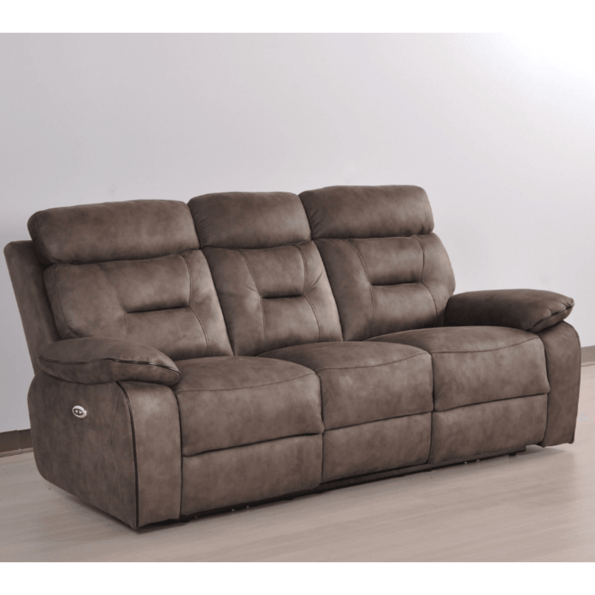 Brown reclining sofa on a light wooden floor with a white wall background