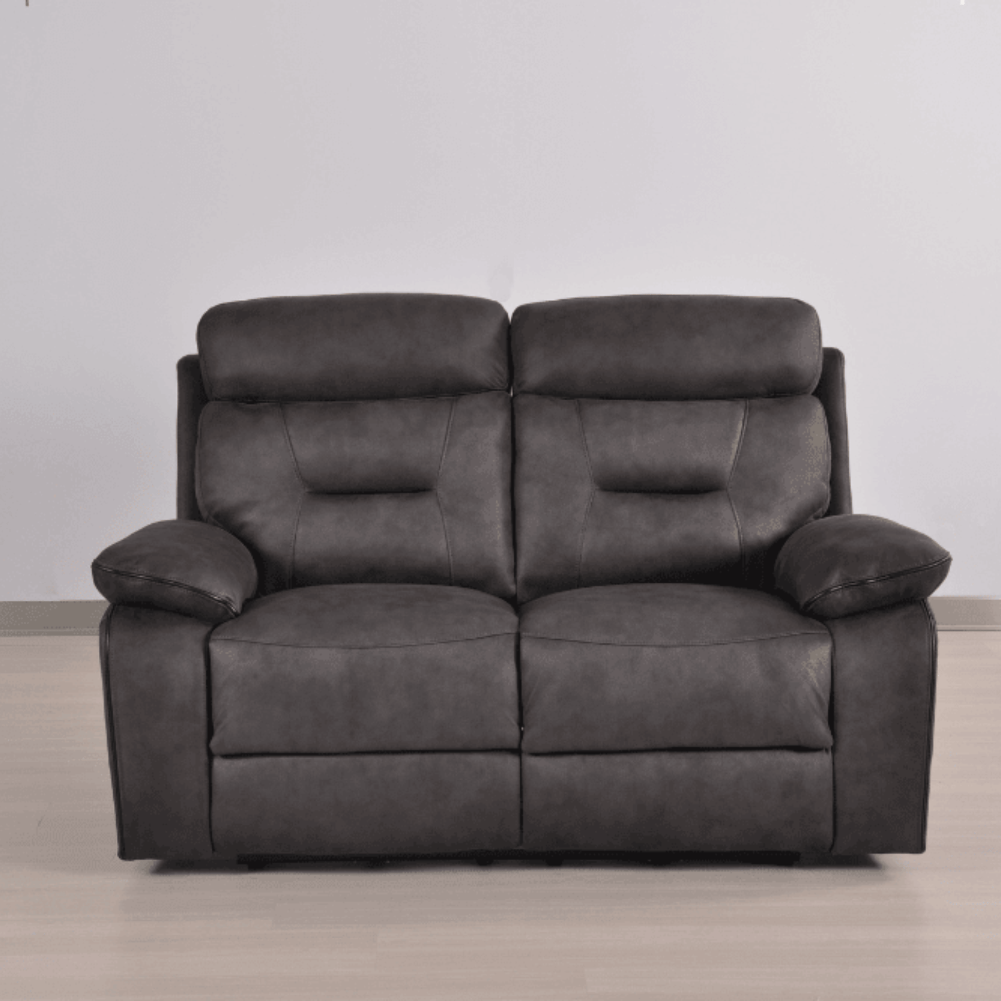 Gray leather sofa on a wooden floor with a plain white wall background