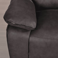Close-up of a dark gray leather armchair with a wooden floor background