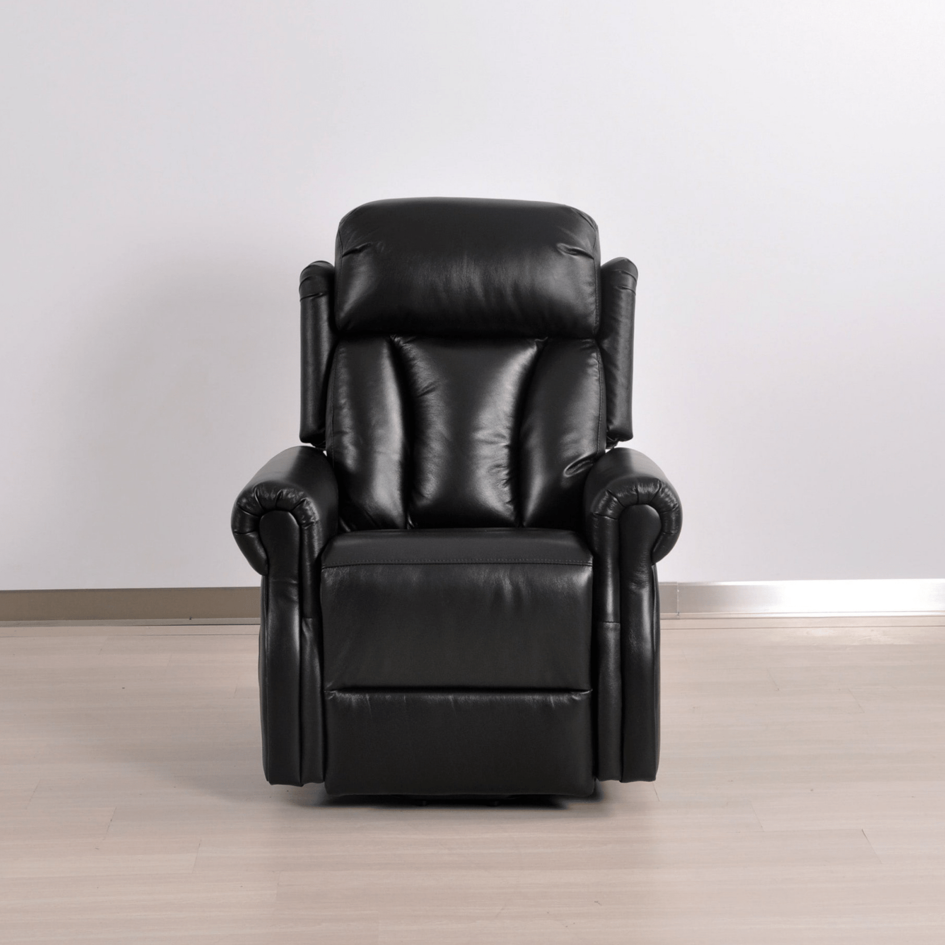 Black leather recliner chair on a wooden floor with a white wall background