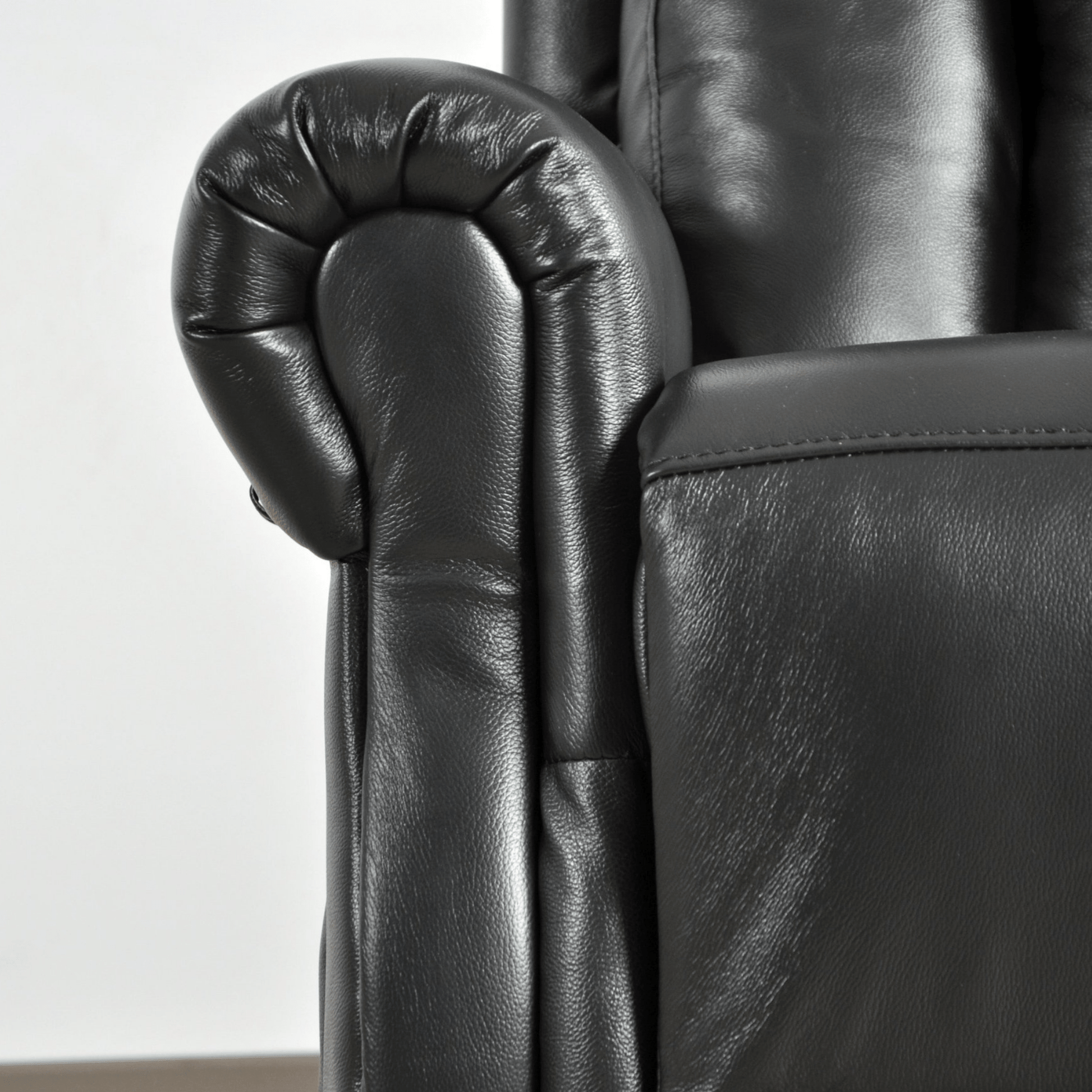 Close-up of a black leather armchair with detailed armrests on a white background