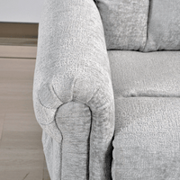 Close-up of a textured gray sofa armrest on a light wooden floor.