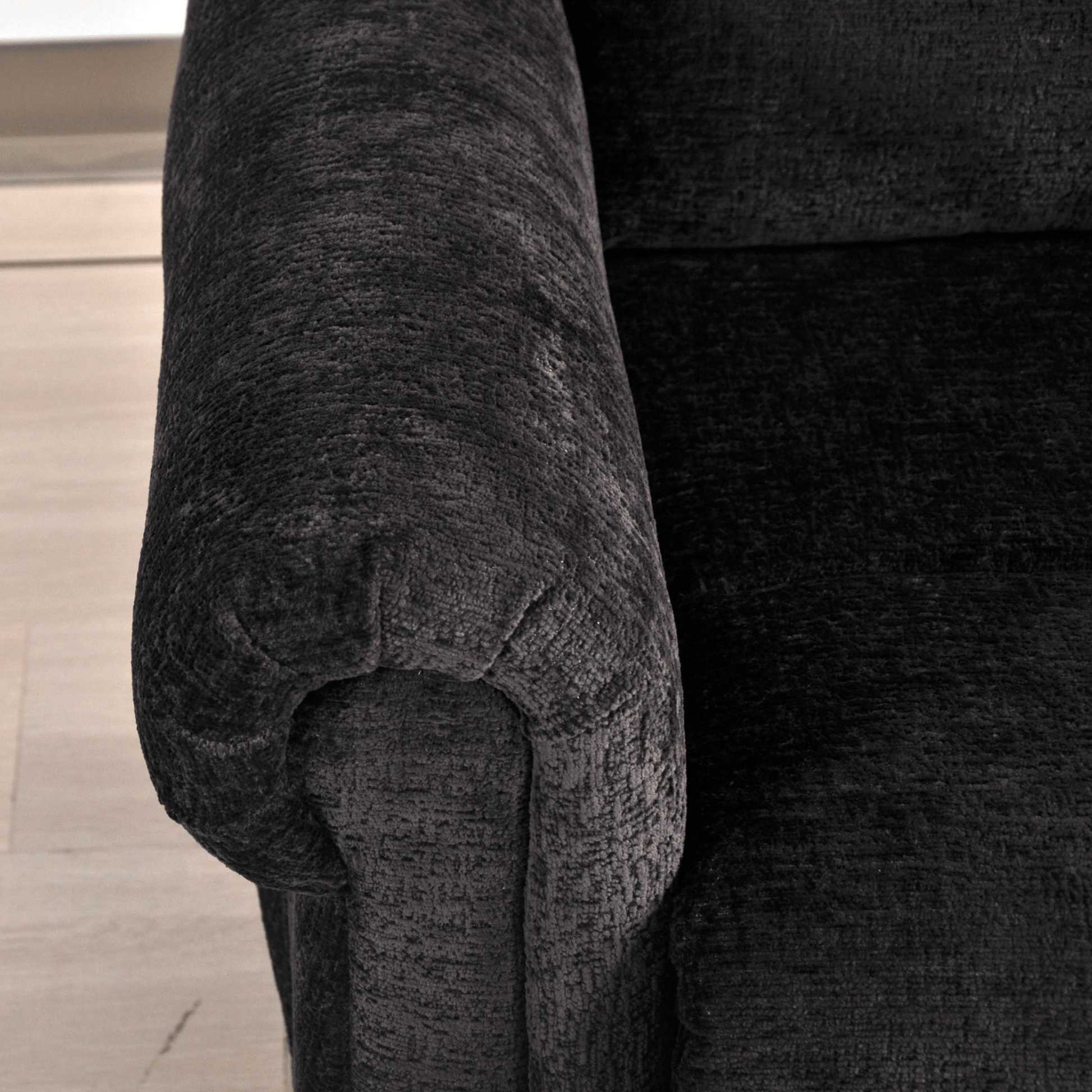 Close-up of a textured black armchair on a wooden floor.