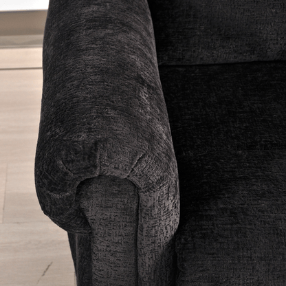 Close-up of a textured black armchair on a wooden floor.