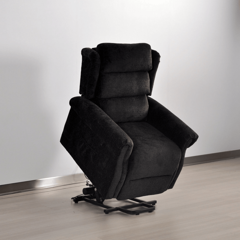 Dark gray recliner chair on a light wooden floor with a white wall background