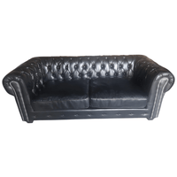Black leather sofa with tufted backrest on a white background