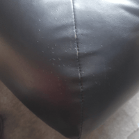 Close-up of a black leather surface with visible stitching