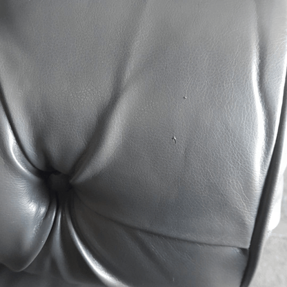 Close-up of a gray leather seat with visible wear and tear.