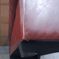 Close-up of a brown leather chair with a visible seam and black plastic component.