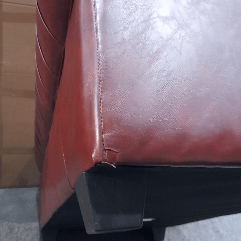 Close-up of a brown leather chair with a visible seam and black plastic component.