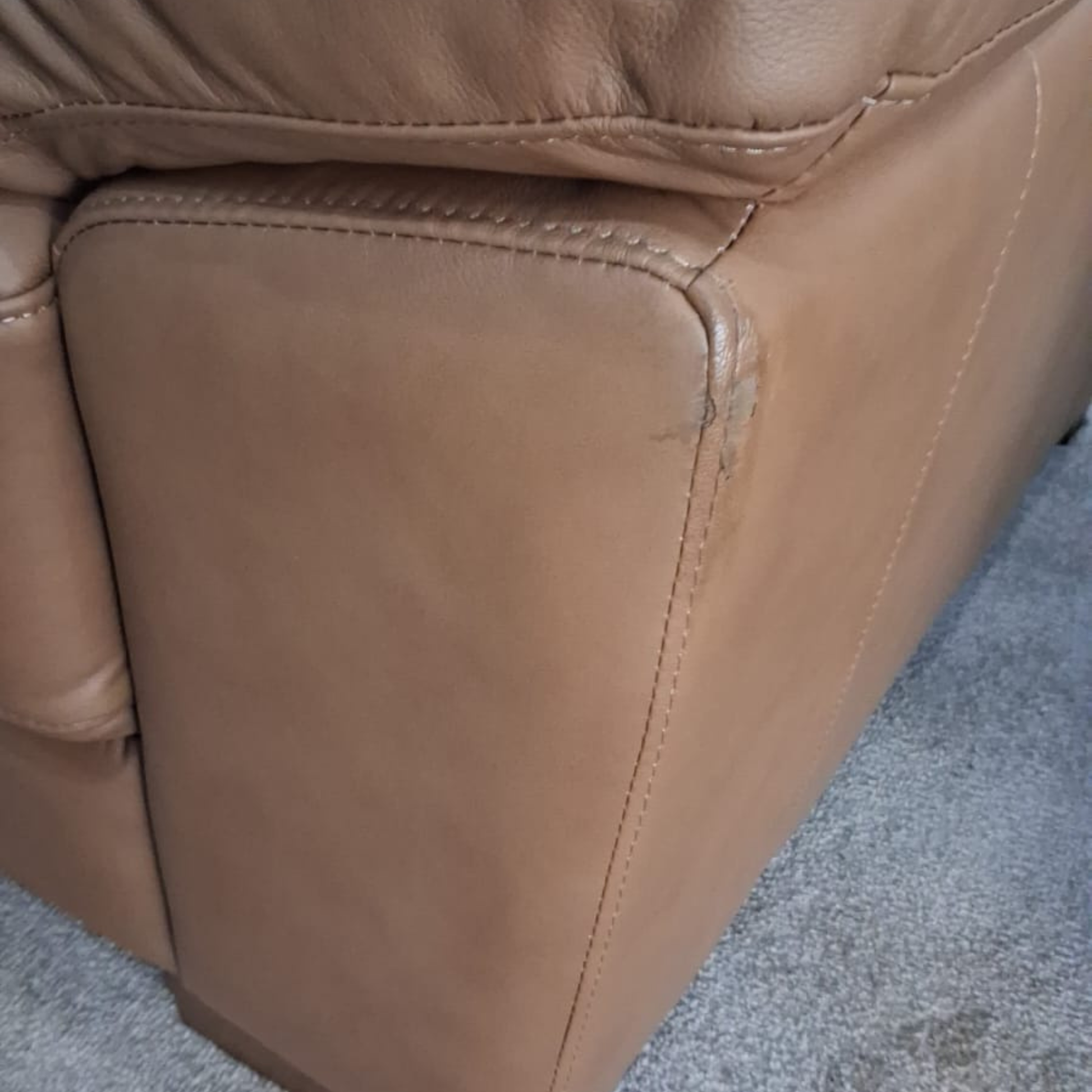 Close-up of a brown leather chair with visible wear on a textured surface