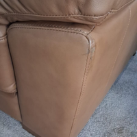 Close-up of a brown leather chair with visible wear on a textured surface