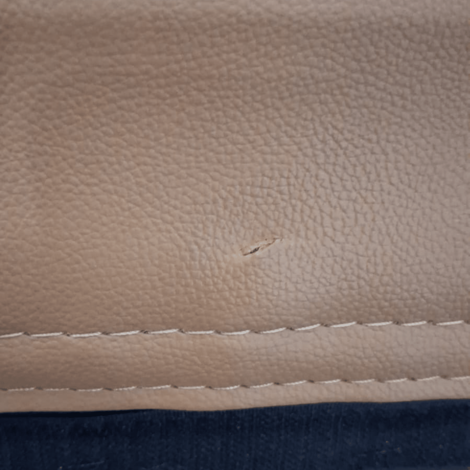 Close-up of a beige leather surface with a small scratch.