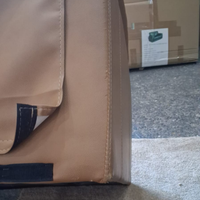 Close-up of a brown leather bag with visible stitching, blurred background