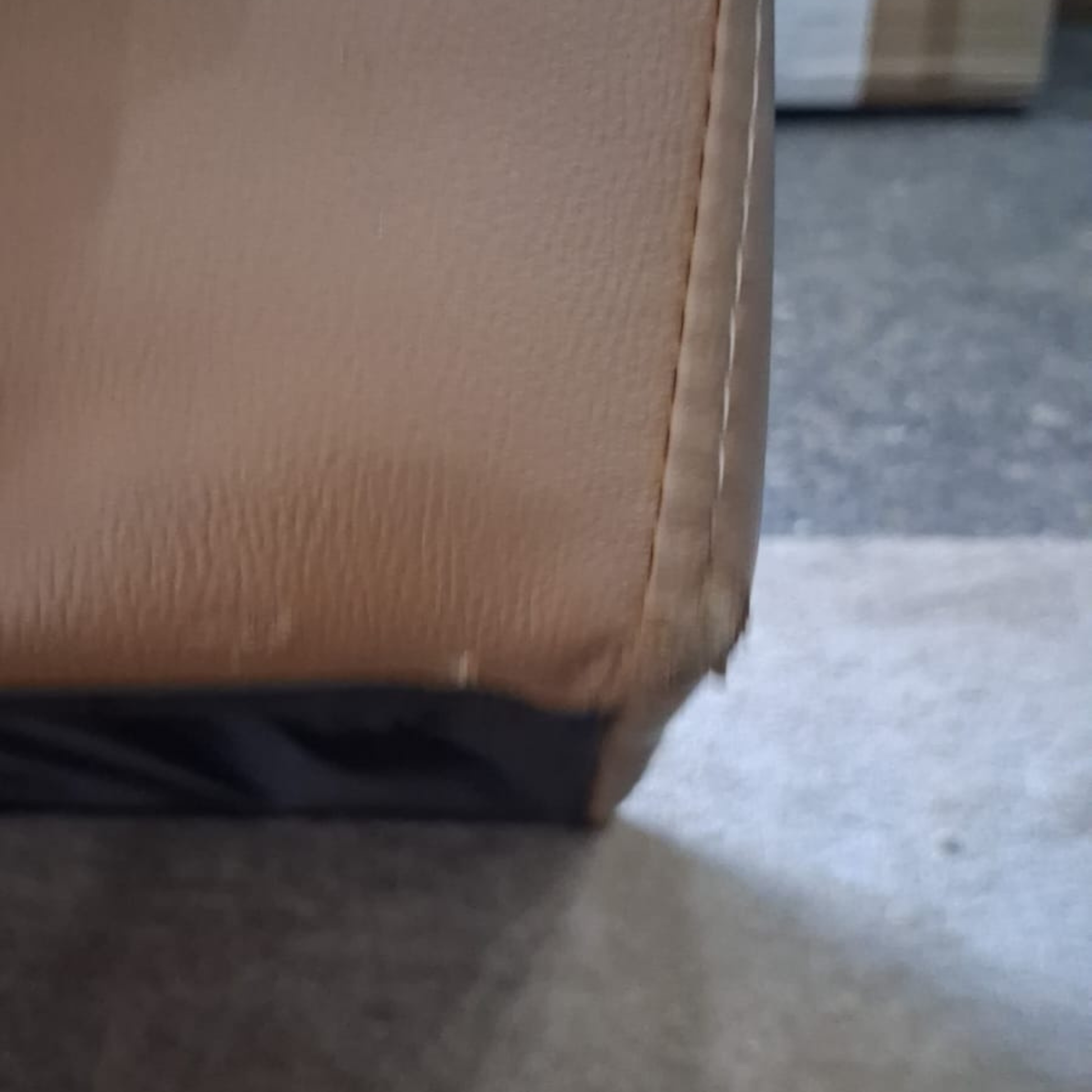 Close-up of a brown leather chair corner on a carpeted floor