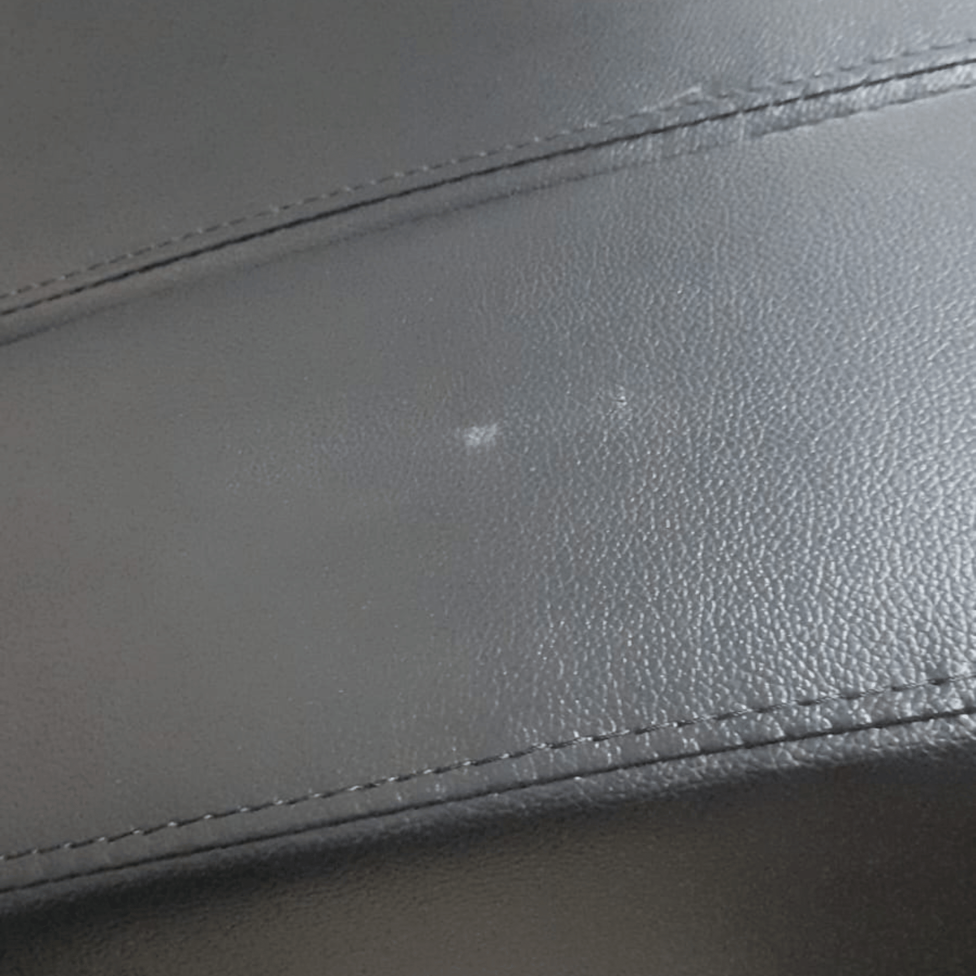 close up of black leather 3 seater showing marks.