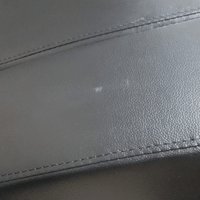 close up of black leather 3 seater showing marks.