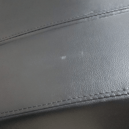 close up of black leather 3 seater showing marks.