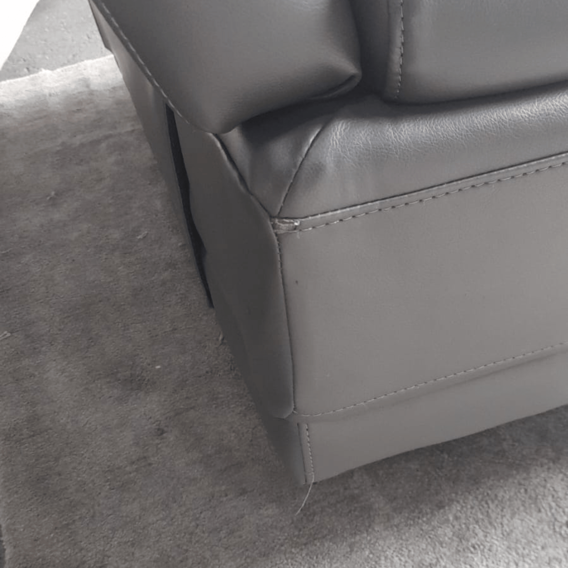 Gray leather armchair corner on a gray carpet