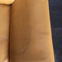 Close-up of a brown leather couch with a dark blue carpet background