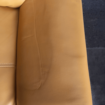 Close-up of a brown leather couch with a dark blue carpet background