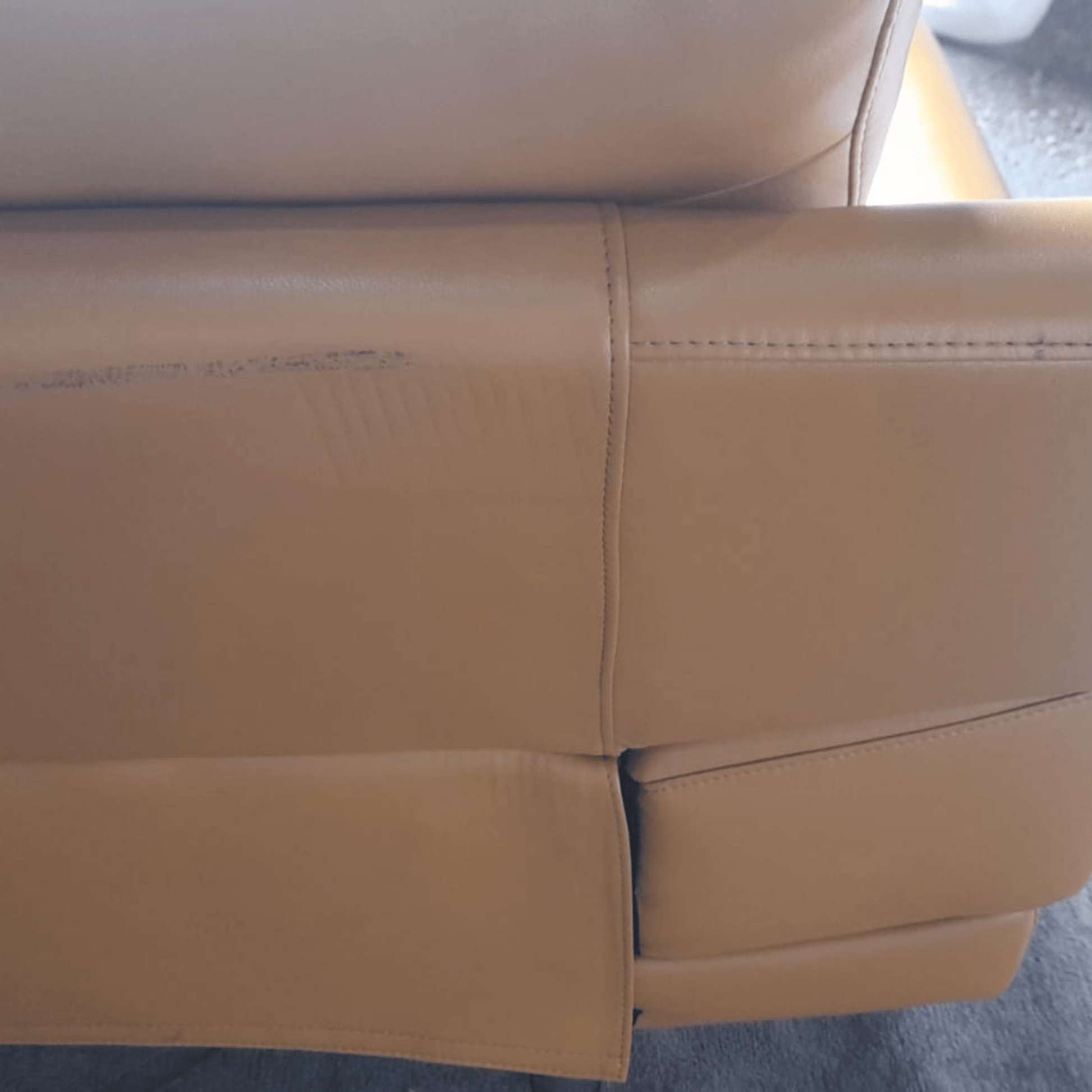 Close-up of a yellow leather sofa with visible wear and tear.