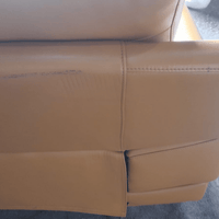 Close-up of a yellow leather sofa with visible wear and tear.
