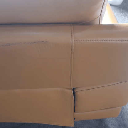 Close-up of a yellow leather sofa with visible wear and tear.