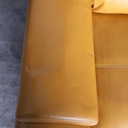 Close-up of a yellow leather sofa with a textured gray background