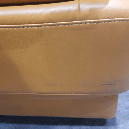 Close-up of a Yellow leather chair with visible stitching on a blue surface.